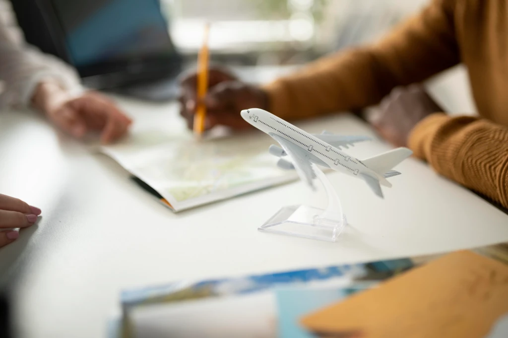 Two person planning aviation management tasks with a model aeroplane and notebook on a desk